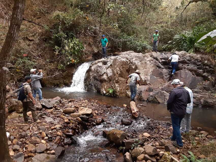 group of people inspecting a water source and waterfall in Honduran forest